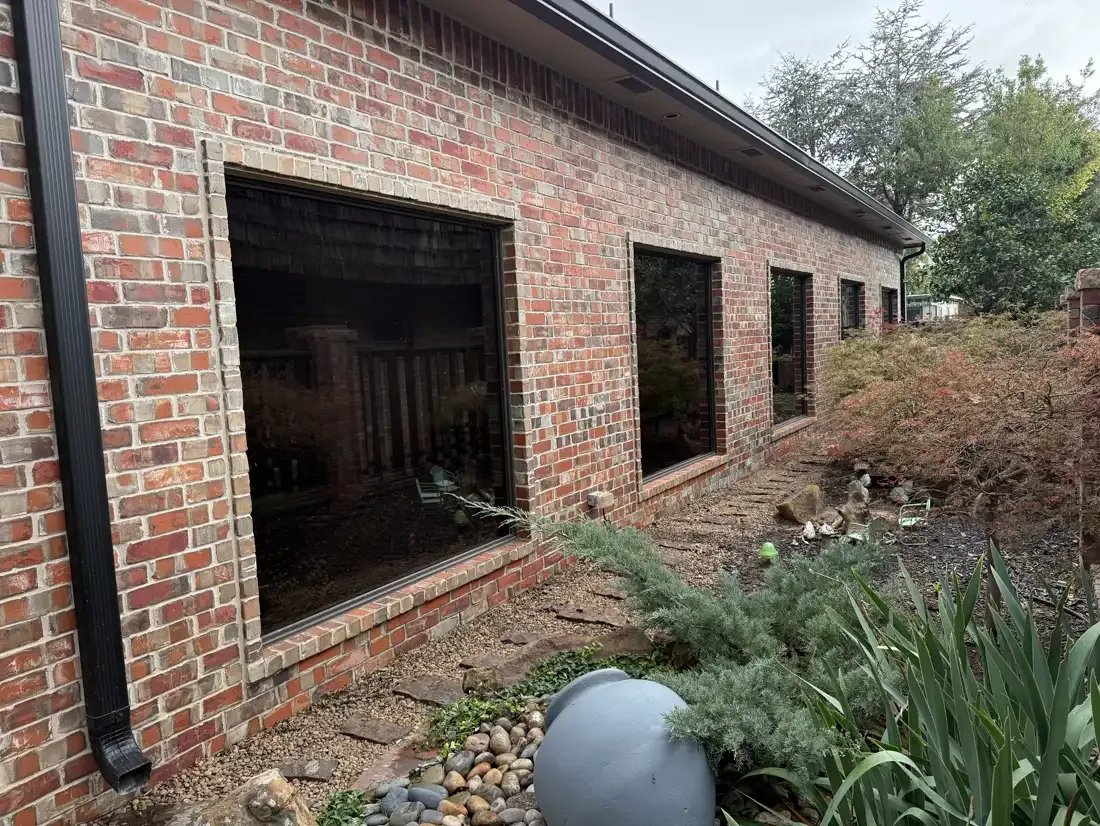 Brick home with four large picture windows darkened by residential window film