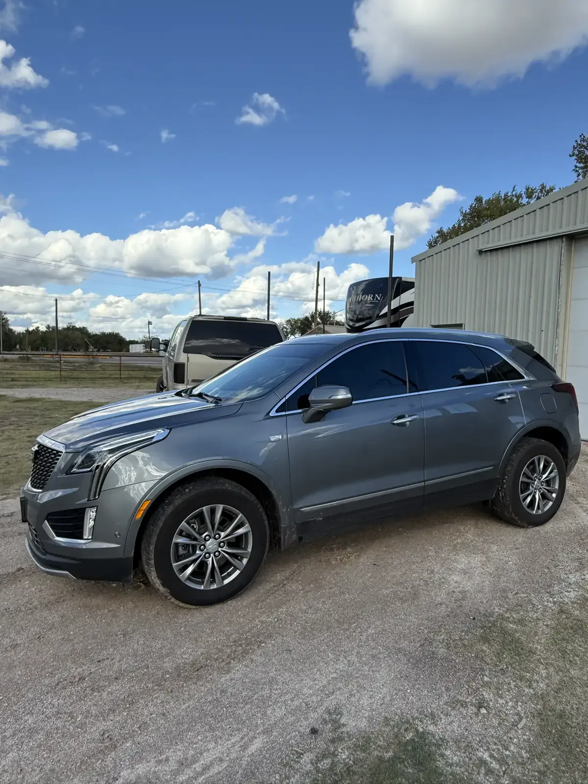 Gray Cadillac XT5 with ceramic window tint installed by EHCO, parked under a blue sky in Northwest Arkansas