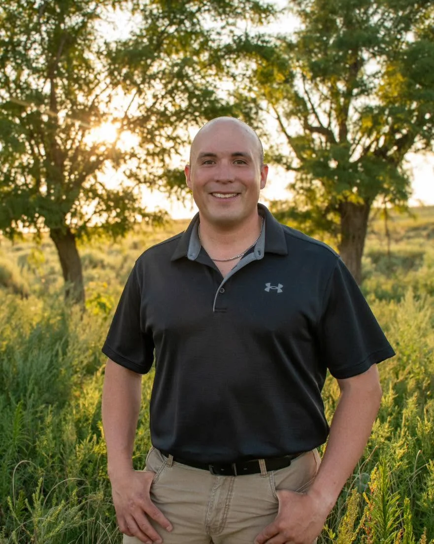 Ethan Haney, owner of EHCO Window Tinting, standing in a field at sunset