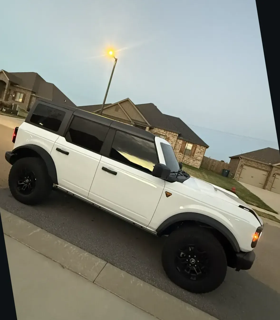 Rear three-quarter profile of the same tinted Ford Bronco under a streetlight