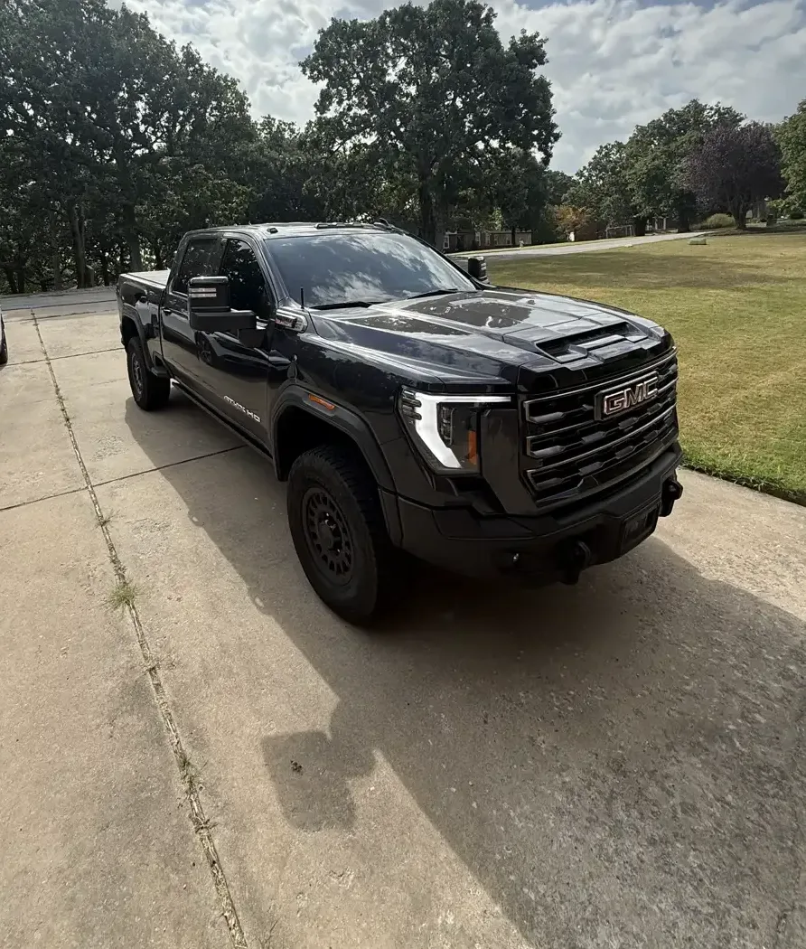 Front three-quarter view of the black GMC Sierra AT4X showing its tinted door glass