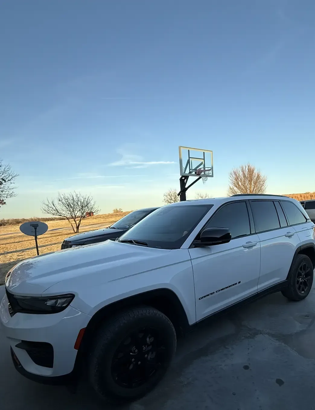 White Jeep Grand Cherokee with dark ceramic window tint at golden hour, tinted by EHCO in Northwest Arkansas
