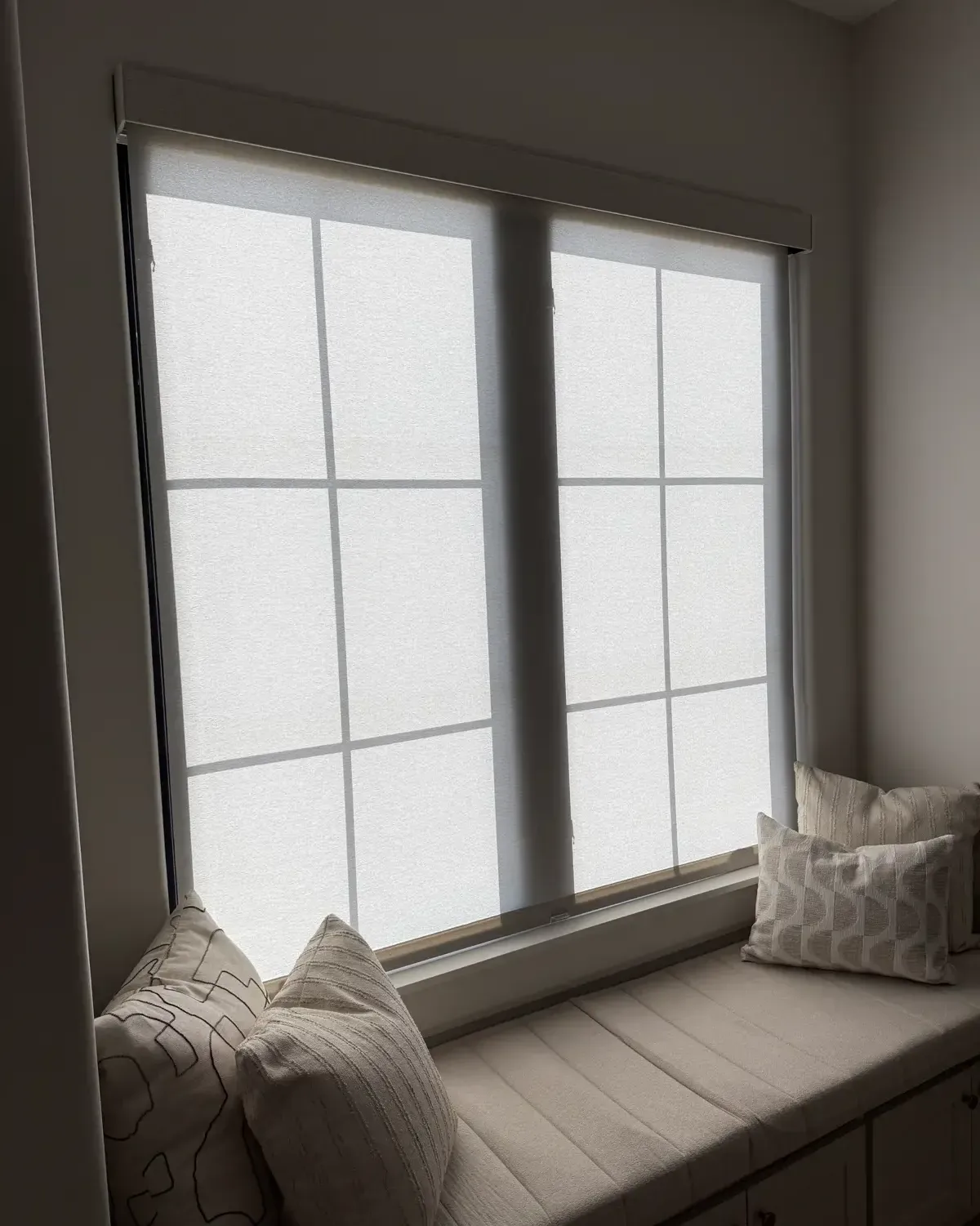 Close view of a custom roller shade lowered above a window seat, showing fabric and fit detail from an EHCO shade installation